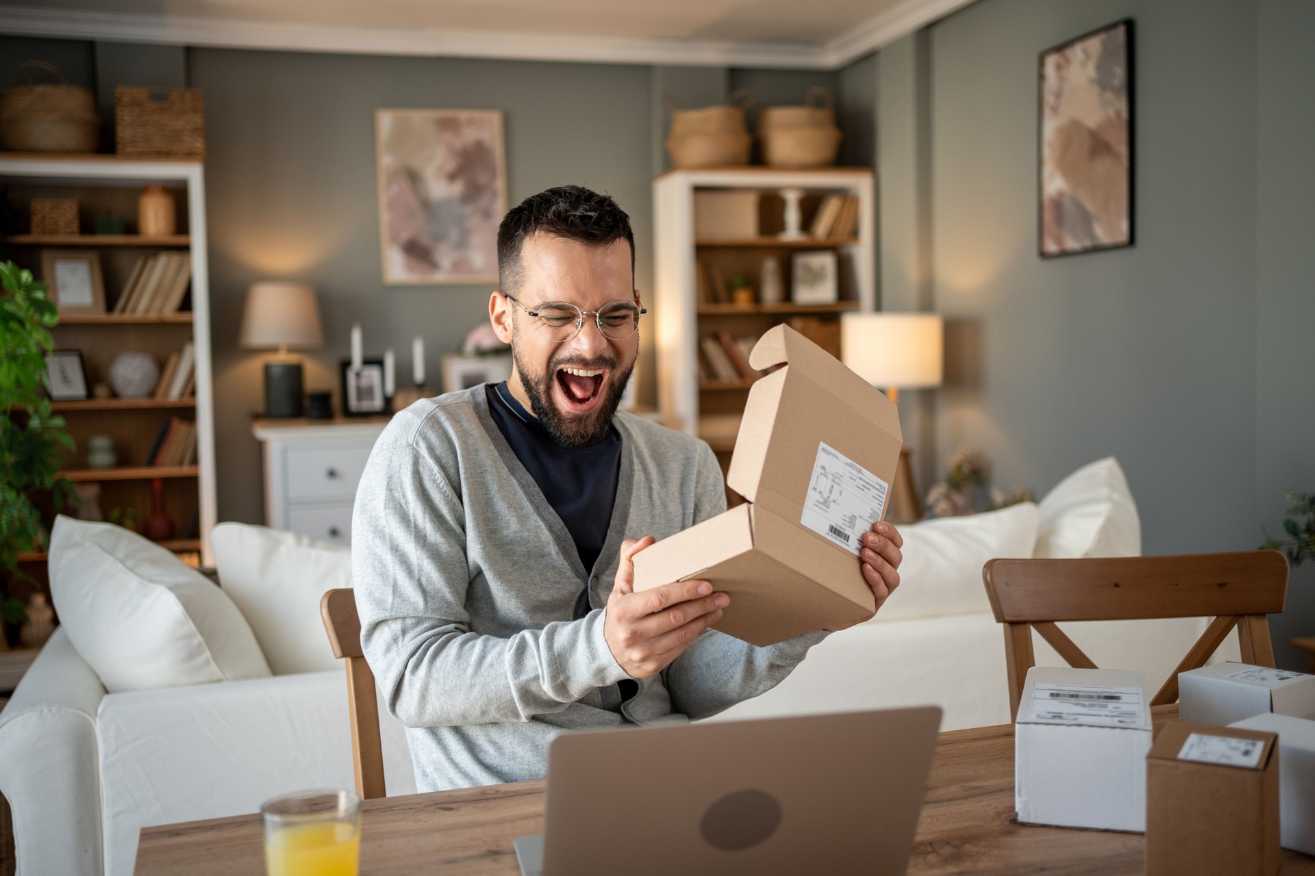Excited man opening parcel at home in living room